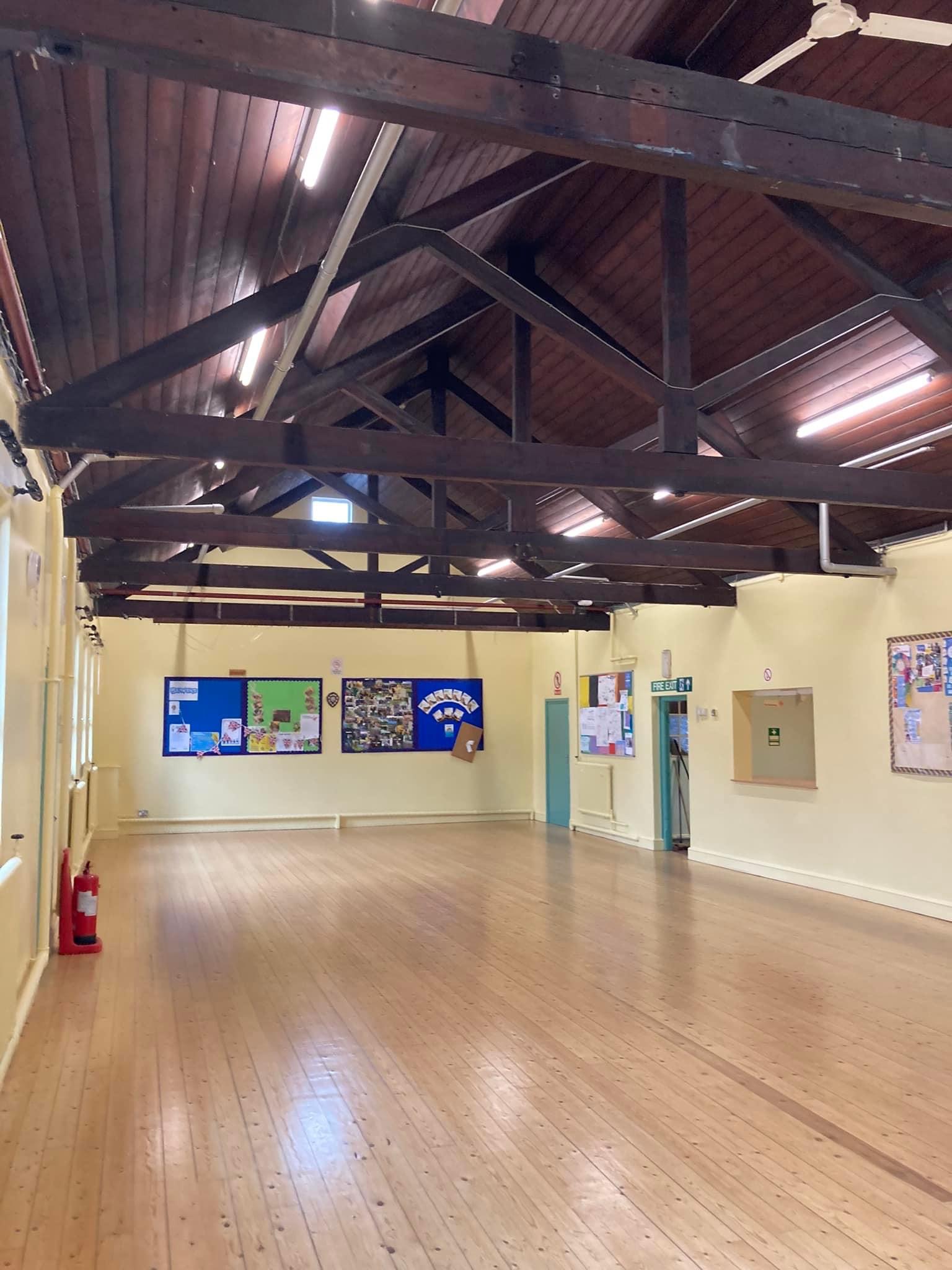 Large hall with exposed dark timber roof trusses and cream walls