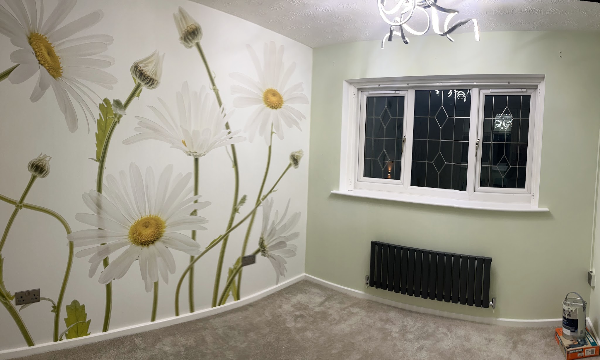 Daisy mural wallpaper on a feature wall in a soft green bedroom